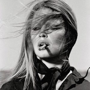 Brigitte Bardot by Terry O'Neill, black and white portrait of the actress in black blouse and scarf, hair blowing in the wind, smoking a cigarette