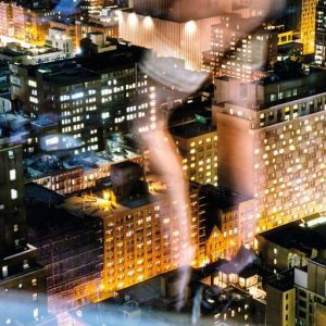 Flashing the City by David Drebin, citylight by night through a window with the reflection of a models legs in stockings