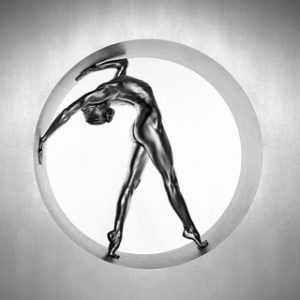 Heima by Guido Argentini, silver painted model bending over backwards in a round enclosure