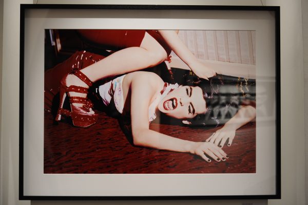 Bitch, Paris by Ellen von Unwerth, two models in red latex skirts, one sitting ontop of the other, holding her down by her hair, framed black