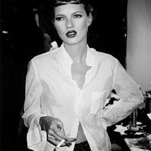 Kate Moss, Milan 1994 by Roxanne Lowit, the model in a white shirt and red lip, smoking