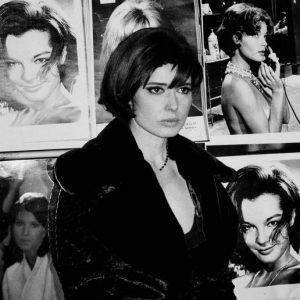 Isabella Rossellini by Rocanne Lowit, portrait of the actress in a fur coat, infront of a wall of actresses' portraits