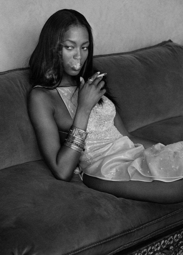 Naomi Campbell Smoking, Morocco by Albert Watson, black-and-white vintage fine art photography showing the supermodel with a cigarette sitting on a sofa wearing a white sequin dress