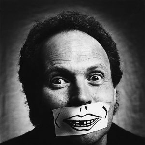 billy crystal by Nigel Parry, black and white portrait of the comedian with a sticker over his mouth with a mouth painted onto it