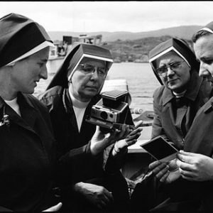 BOAT PASSENGERS by Arthur Elgort, four Nuns sitting in a boat, looking at an instant camera