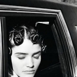 Helena Christensen. 1990 by Arthur Elgort, the model in tied up curlsenjoying the sun out of a carwindow with closed eyes