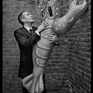 jeff koons, in my Stairwell by Mark Seliger, black and white portrait of the artist in front of a brick w3all, holding a giant blow up lobster