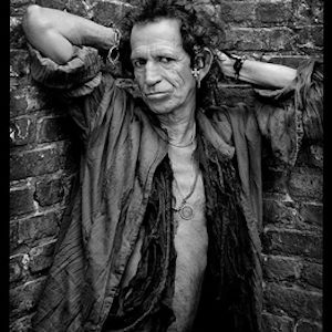 Keith Richards, in my Stairwell by Mark Seliger, portrait of the musician in an unbuttoned shirt, posing in a corner between two brick walls, hands behind his head