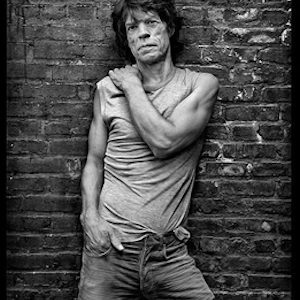 mick jagger, in my stairwell by Mark Seliger, the musician in jeans and shirt posing in front of a brick wall