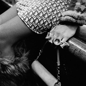 Dior Prêt à Porter, Paris 2000 by Gérard Uféras, closeup of model in dior skirt and rings holding a bag sitting on a bar