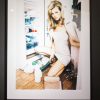 Kate Moss Shopping, by Ellen von Unwerth, the model in a pink nightgown and woolcoat draped over her shoulder, unpacking groceries in front of the open fridge, framed black
