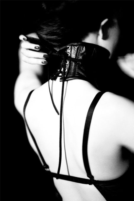 halskrause 2010 by Ellen von Unwerth, model in black bra and corset choker from the back