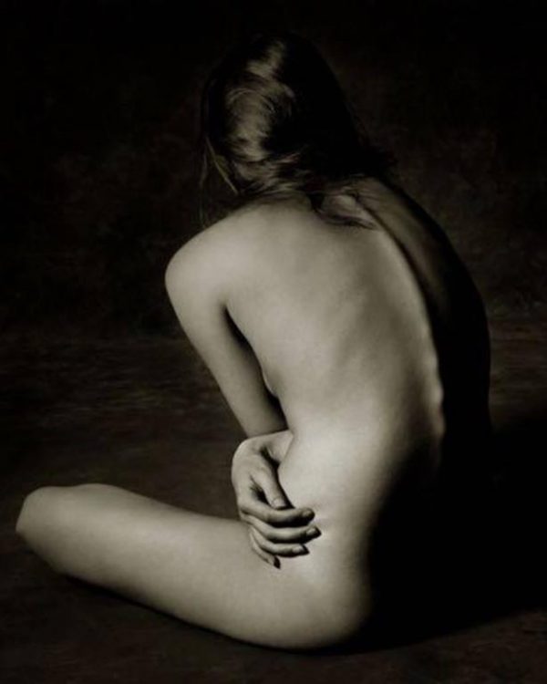 Kate Moss Back, Marrakesch 1993 by Albert Watson, the nude model sitting on the ground, back turned to the camera, hugging herself