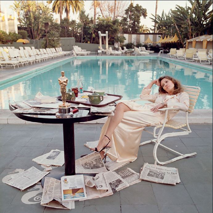 faye dunaway by the pool by Terry O'Neill, the actress in a white gown sitting by the pool surrounded by Newspaper and her Oscar