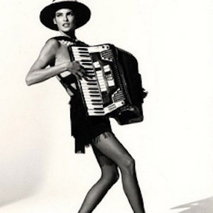 Linda Evangelista playing by Arthur elgort, the model in short dress, heels and hat, playing accordeon