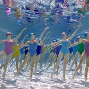 Corps du Ballet Underwater Study #3094 by Howard Scahtz, models in colorful simsuits and matching swimcaps and goggles dancing underwater in a pool