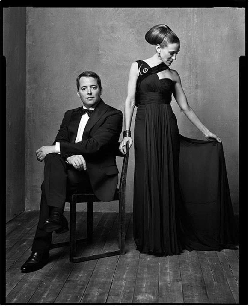 Mathew Broderick and Sarah Jessica Parker by Mark Seliger, matthew in a black suit sitting on a chair, right next to hom sarah jessica Parker in a black own with broach