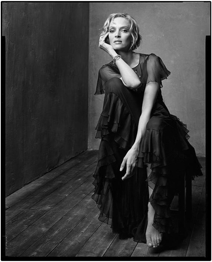Uma Thurman by Mark Seliger, the actress in a black ruffle dress sitting on a chair