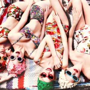 Freshly Bloomed by Ellen von Unwerth, four models in vintage bathing suits and bikinis in flowerprint with matching caps and sunglasses lying on a towel at the beach