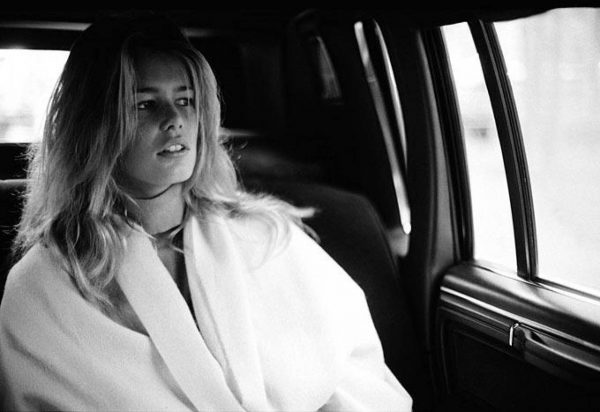 Claudia Schiffer by Antoine Verglas, portrait of the model i a white blouse sitting in a car, looking out the window