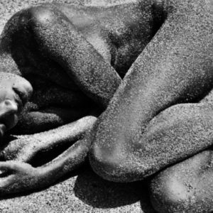 Petra Grand Fond, Shell Beach. 2015, nude model covered in sand lying on the ground crouched together