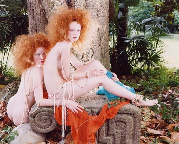 Red Hair 1 by Iris Brosch, two nude models with curly red hair covered in pearl chains posing in a garden