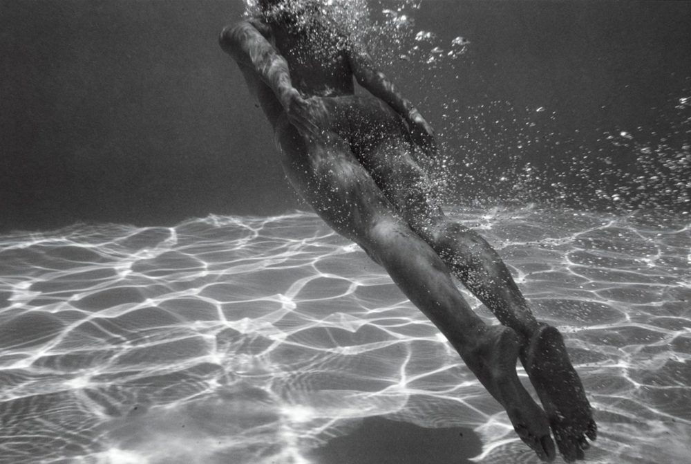 Tove Underwater Reflections from the nudes in nature series by Guido Argentini, nude model floating underwater between airbubbles and sun reflections