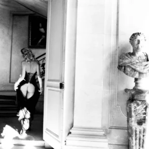 Story of Olga by Ellen Von Unwerth, model with exposed butt walking towards a staircase, a marble bust in the foreground