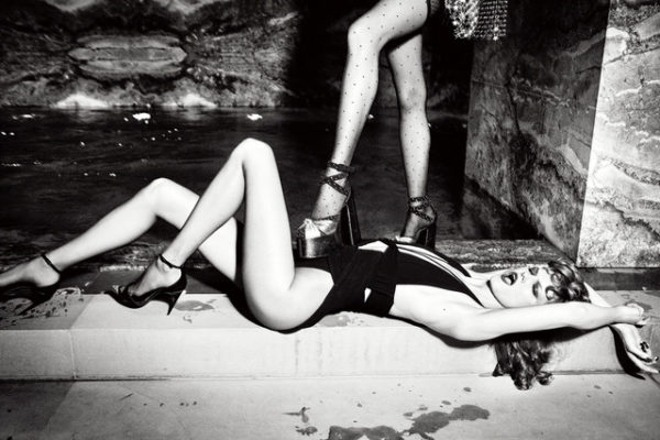 In Trouble, for Vogue Poland by Ellen von Unwerth, model in swimsuit and heels lying on the floor, another models foot in tights and heels placed on her belly