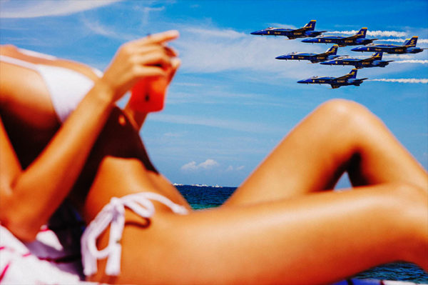 Avion de Chasse by Tony Kelly, model in white bikini and the ocean and six blue fight jets in the back