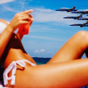 Avion de Chasse by Tony Kelly, model in white bikini and the ocean and six blue fight jets in the back