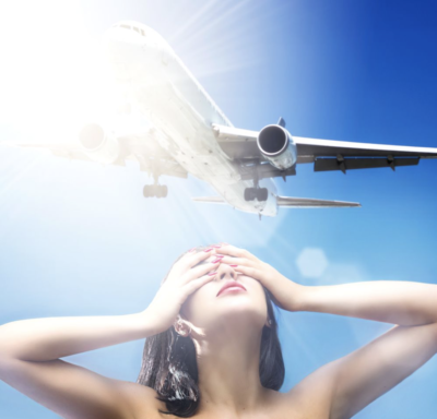 Airplane Lover by David Drebin, model holding her hands in front of her eyes while airplane flys above her in front of the blinding sun
