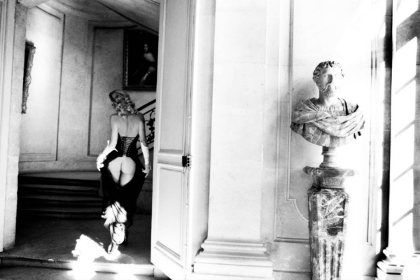Story of Olga by Ellen Von Unwerth, model with exposed butt walking towards a staircase, a marble bust in the foreground