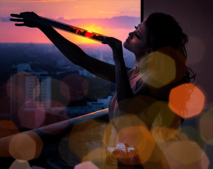 Sunset Lover by David Drebin, model on a balkony, holding a filmstrip into the sundown, lens flare