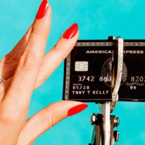 unbreakable by tony kelly, hand with red nails and diamond ring holding a black american express card which is being cut in half by sturdy scissors
