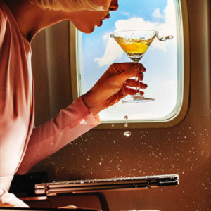 Turbulence by Tony Kelly, model in front of airplane window trying to sip on her cocktail while the liquis is spilling out