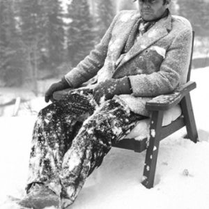 Jack Nicholson Aspen 1981 by Albert Watson, the actor in a woolcoat and newspaperboy cap covered in snow, sitting in a chair outside