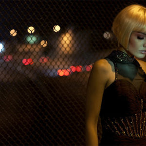 Candice thinking about tomorrow by Guido Argentini, model in blonde wig standing in front of a fence next to a street