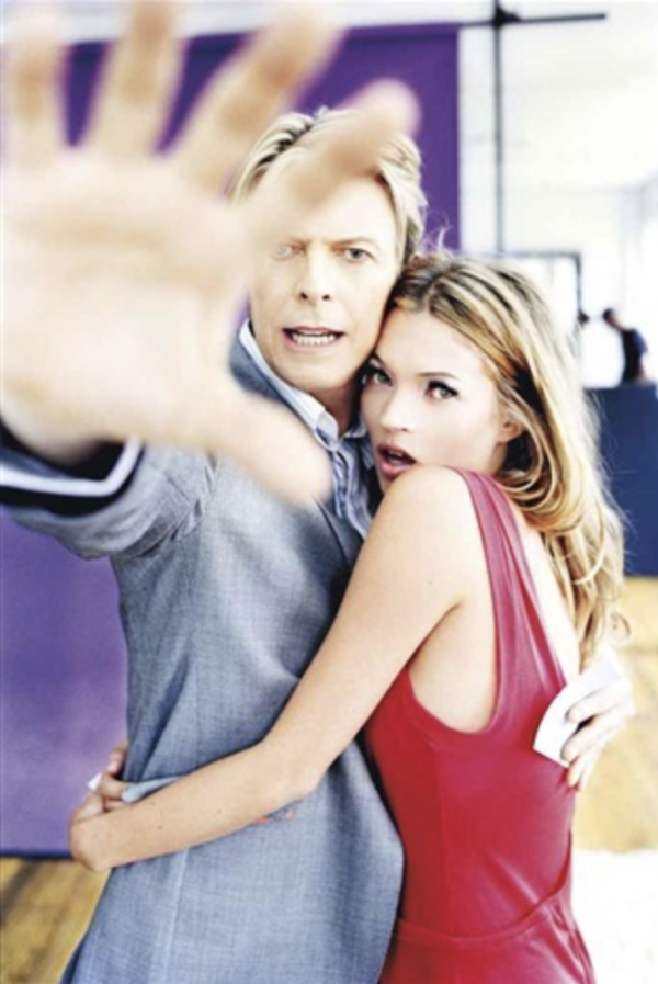 David Bowie & Kate Moss, Colour by Ellen von Unwerth, Bowie and Moss hugging while Bowie is trying to shield them from the camera