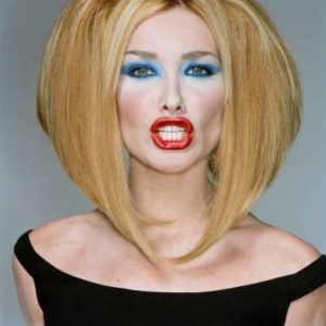 Caral Bruni, Vogue by Michel Comte, the model in a blonde wig blue eyeshadow and red lip