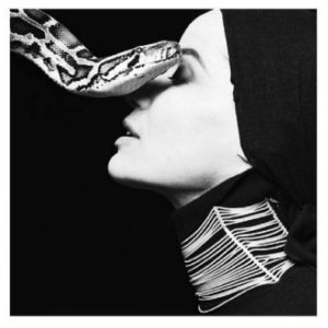 Veruschka Snake by Michel Comte, model in side profile in turtleneck and headscarf, wearing a big choker, a snake next to her face