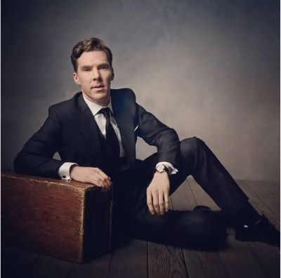 Benedict Cumberbatch by Mark Seliger, the actor in a black suit sitting on the ground leanig a gainst a wooden block