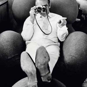 Sean Connery with Camera by Terry O'Neill, the actor in white sitting on a Gaetano Pesce armchair and pointing a camera
