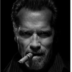 Arnold Schwarzenegger by Tinothy White, black and white portrait of the body builder with a cigar