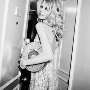 Claudia Schiffer ''The Movies in a Can'' by Roxanne Lowit, the model in a sparkling flapper dressy carrying a film roll in a hallway