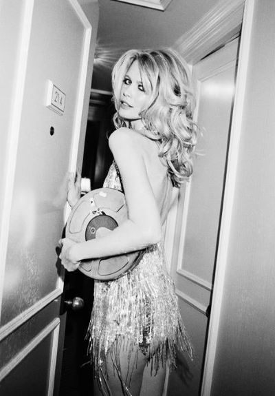 Claudia Schiffer ''The Movies in a Can'' by Roxanne Lowit, the model in a sparkling flapper dressy carrying a film roll in a hallway