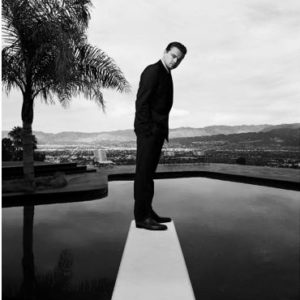 Leonardo DiCaprio, Bond by Nigel Parry, the actor in a black suit standing on a springboard above a pool with a palm tree