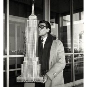 Yves St Laurent, NY 1983 by Roxanne Lowit, the designer holding and kissing a model of the Empire State Building