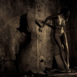 Francesca Gold II by guido argentini, nude model leaning at an old wall