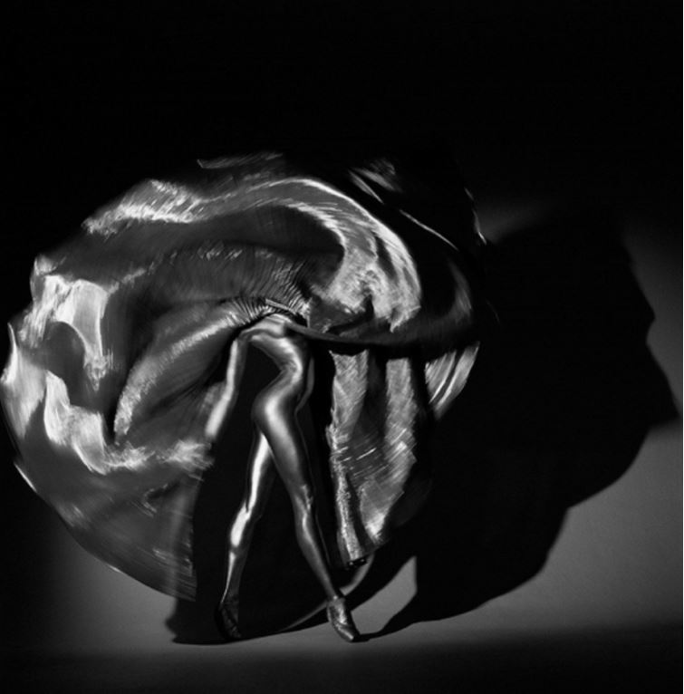 Inanna by Guido Argentini, silver painted dancer twirling with silver pleated skirt